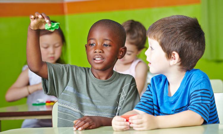 Children playing together, sat at desks