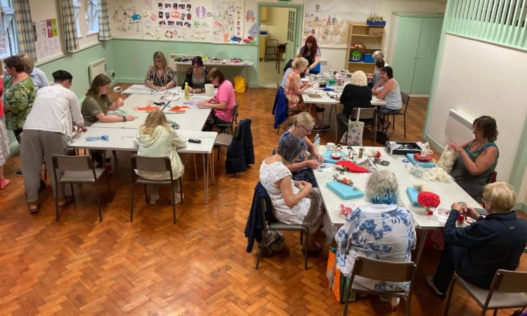 Three tables of people making crafts out of fabric