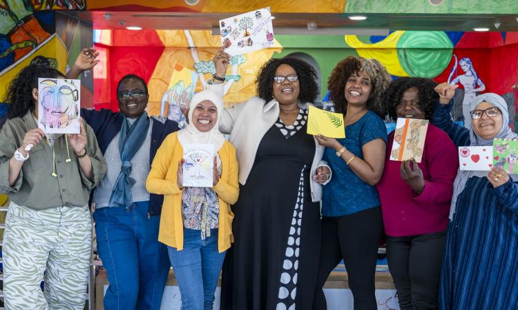 Group shot of an art session with participants holding up homemade postcards