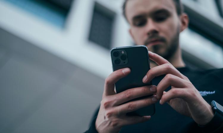 A man looks down at a mobile phone