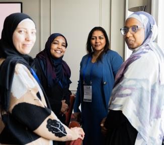Four women smiling facing the camera at a conference