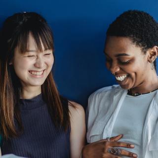 Young people laughing and looking at a notebook