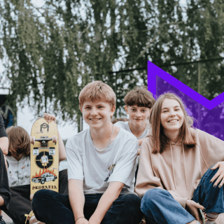 A group of young people sitting on the ground in a skate park