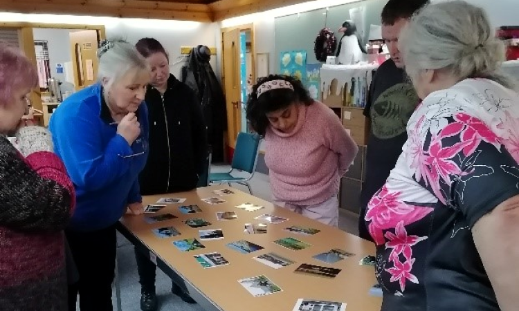A group of people crowded around a table, looking at photos