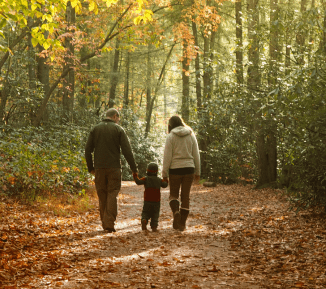 Two adults and one child walking together in a woods